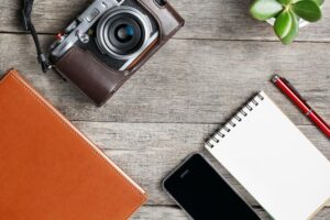 classic-camera-blank-notepad-page-red-pen-gray-wooden-vintage-table-telephone-green-flower-brown-notebook-concept-140388475-1-300×200